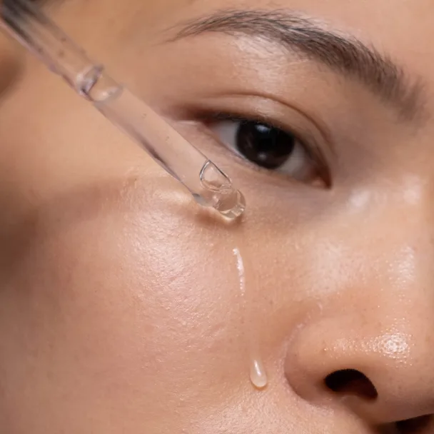 Close-up of a dropper applying a serum near the eye area