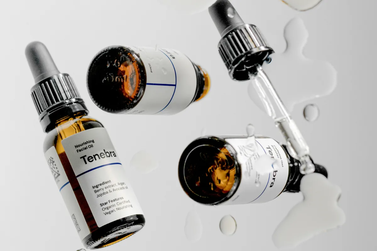 Gros plan sur des flacons compte-gouttes ambrés et des emballages cosmétiques couverts de gouttes d'eau, illustrant les cosmétiques de marque privée de Selfnamed.