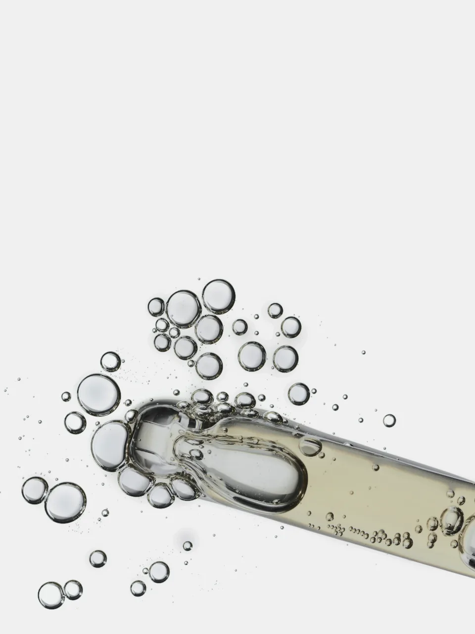 Close-up of a glass pipette dispensing a clear serum with rising bubbles