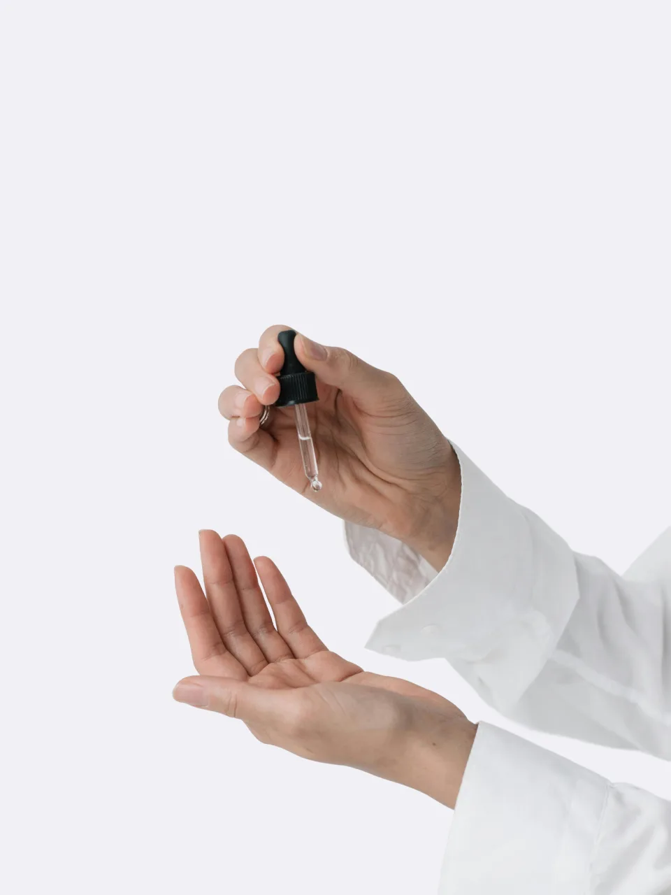 Hands holding an open dropper bottle, demonstrating a clean skincare formula